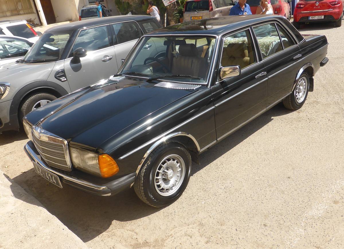 Černý Mercedes-Benz 240 D řady 123 zaparkovaný na dvoře, pohled shora zepředu na celistvou střechu