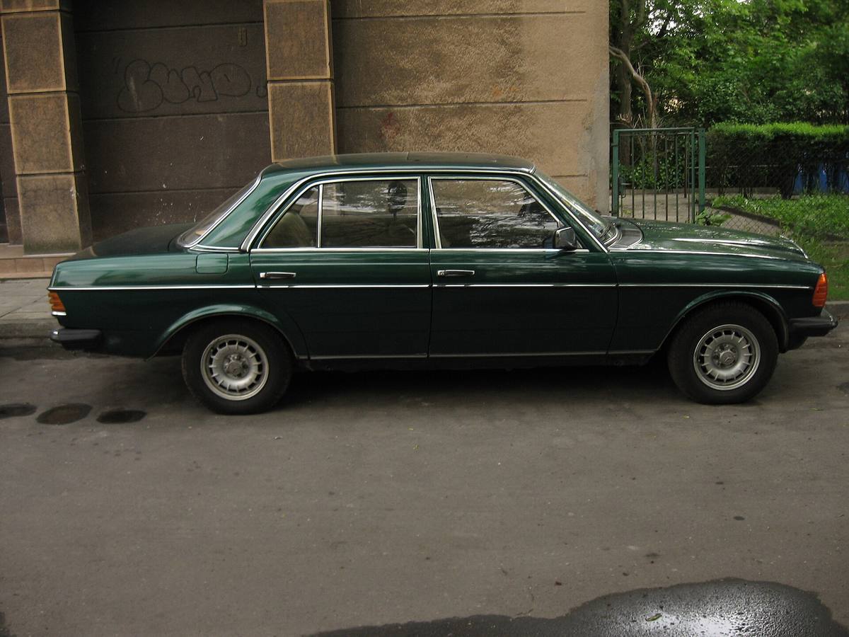 Zelený sedan Mercedes-Benz W123 zboku, v celé délce je vidět práh mezi předním a zadním kolem