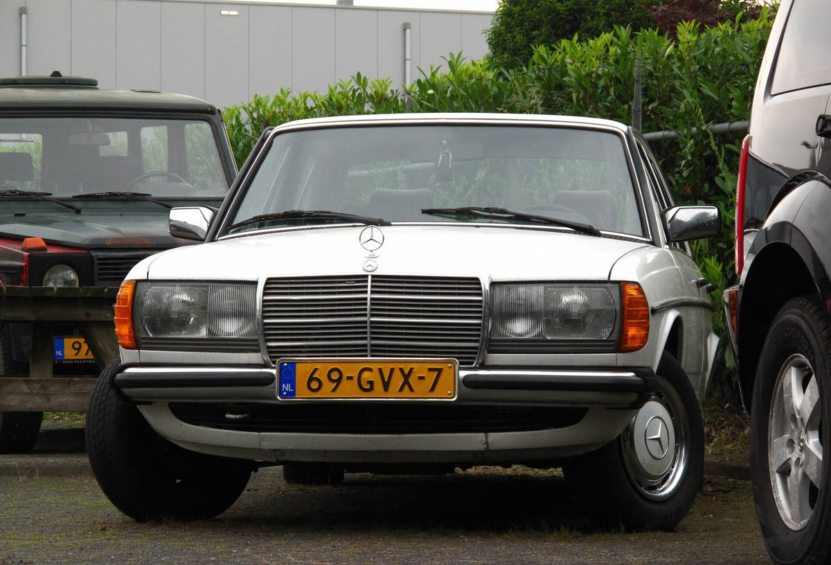 Bílý sedan Mercedes-Benz 200 řady 123 zepředu, s obdélníkovými světlomety a nizozemskou registrační značkou