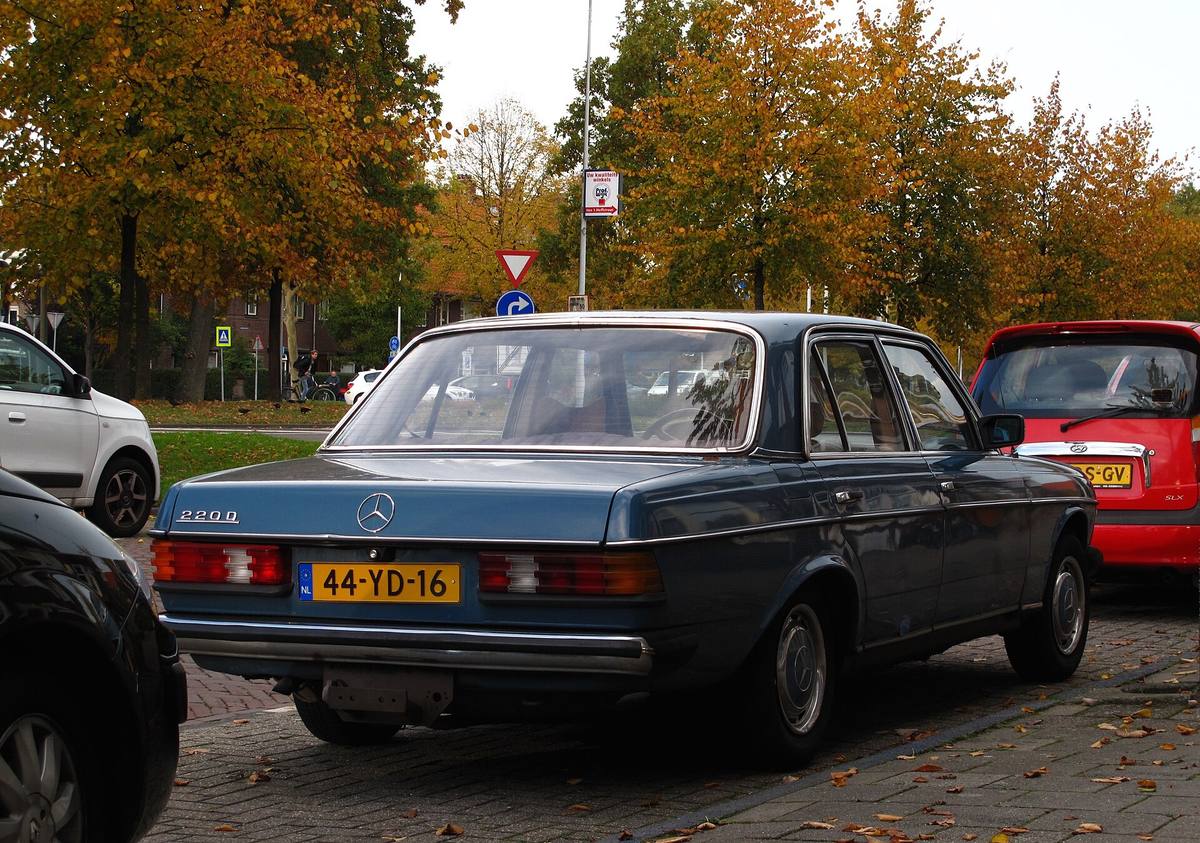 Modrý sedan Mercedes-Benz 220 D řady 123 zezadu na parkovišti