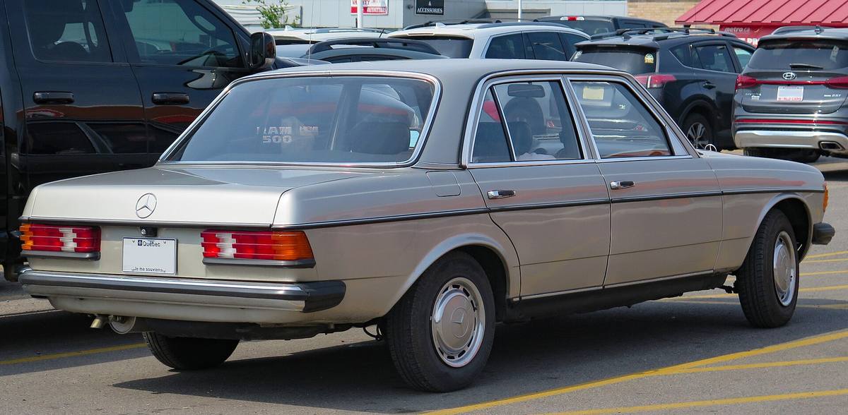 Béžový Mercedes-Benz řady 123 zezadu zprava, s viditelným víkem kufru a zadním blatníkem