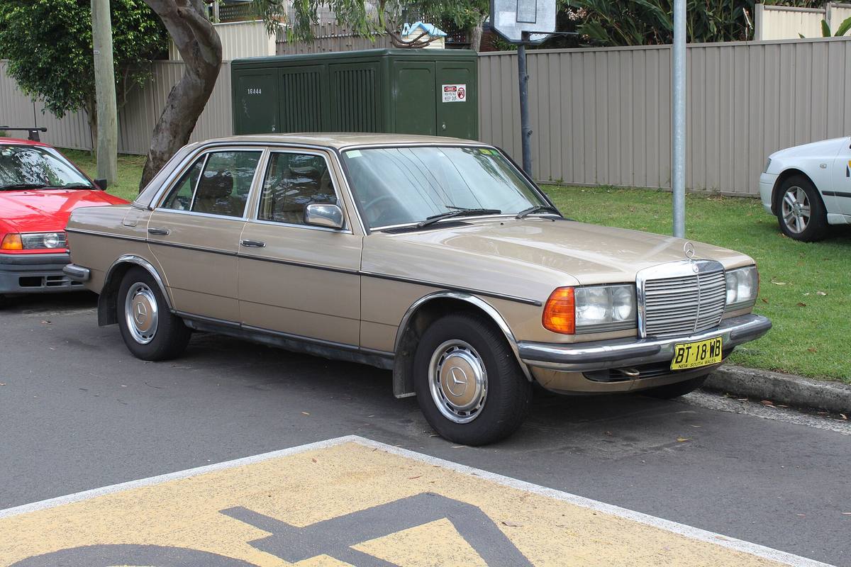 Béžový sedan Mercedes-Benz 280 E řady 123 z roku 1984 zaparkovaný u chodníku